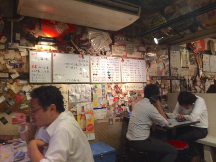 The interior walls are covered in business cards, menus, and posters