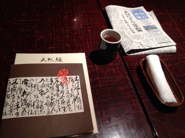 Menu, tea, towel, and a newspaper set at the table