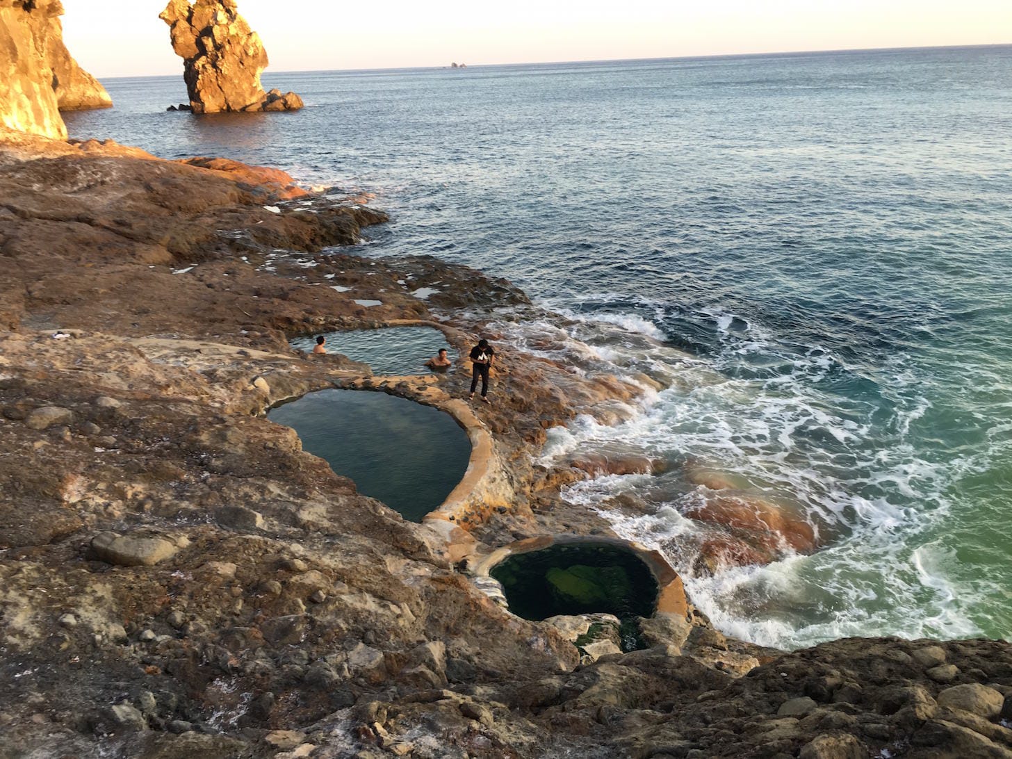 Natural hot spring pool with rocks piled as makeshift changing area