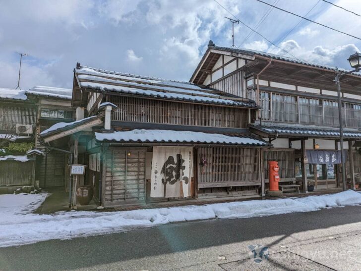 The iconic storefront of Sennen Sake Kikkawa with traditional architecture and a salmon curtain