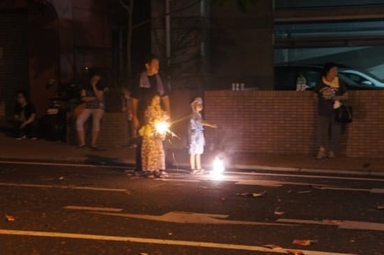 Spectators setting off fireworks by roadside