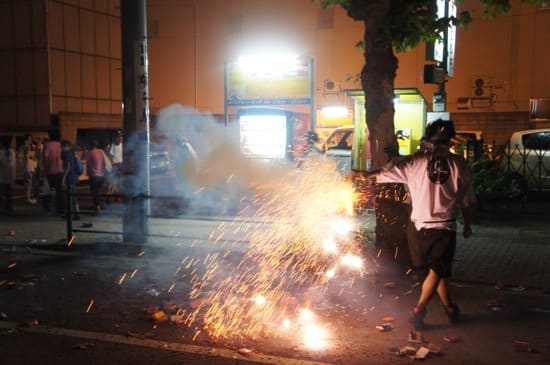 Spectator holding firecracker amidst procession