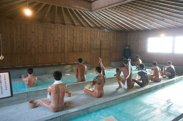 Prison bathhouse with tattooed figures
