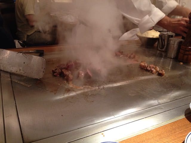 Meat being expertly cooked by two chefs