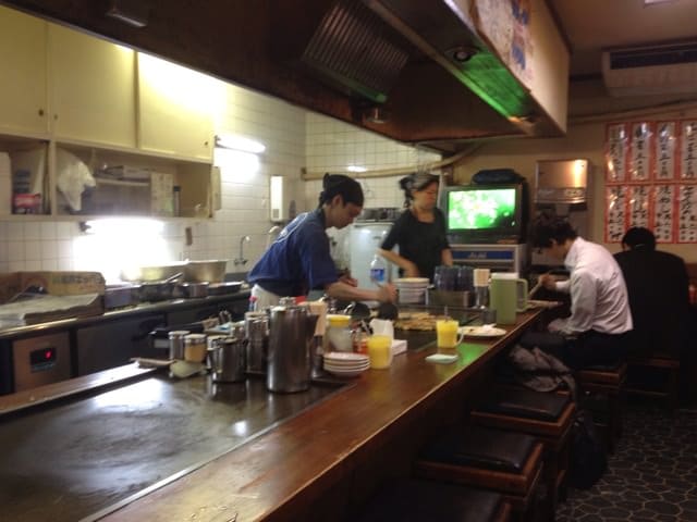 Chef cooking okonomiyaki on griddle